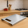 Stainless steel cutting board on a kitchen counter with a blurred background